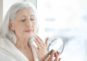 Femme de 6O ans regardant le miroir