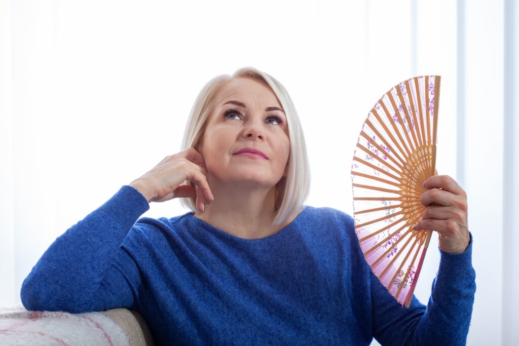 Ménopause : gestion du stress et bien-être émotionnel Femme mature avec une bouffée de chaleur de la ménopause.