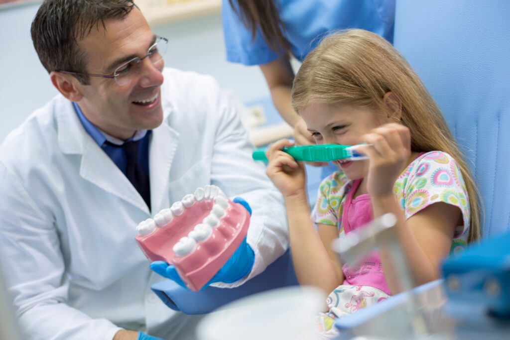 Quand faut-il se rendre dans un cabinet d’orthodontiste ? Un orthodontiste souriant avec une petite fille