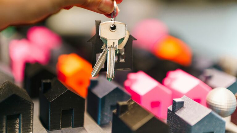 Main tenant des clés au-dessus de maisons miniatures