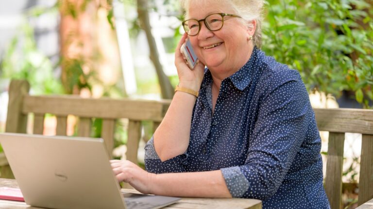 Retraitée au téléphone devant son ordinateur, en train de gérer ses contrats