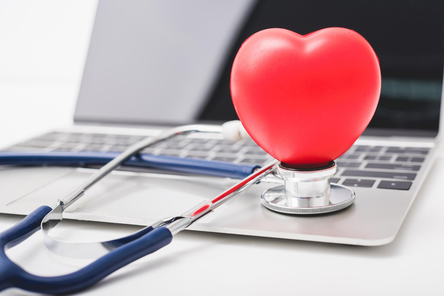 Stéthoscope de santé et coeur rouge sur le clavier d'un ordinateur portable